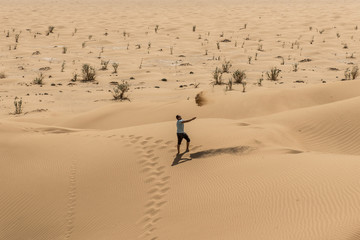 Man tourist in desert rub al khali Oman throwing sand 2