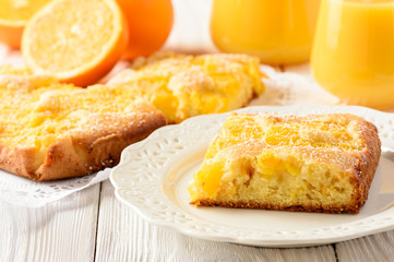 Orange cake and orange juice on white wooden background.