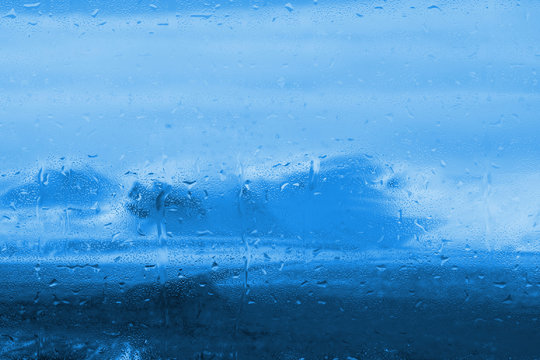 Fototapeta raindrops on a window with frozen bluish mountainous landscape outside
