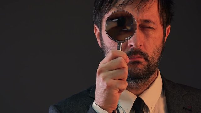 Enlarged eye of tax inspector looking through magnifying glass, inspecting offshore company financial papers, documents and reports.