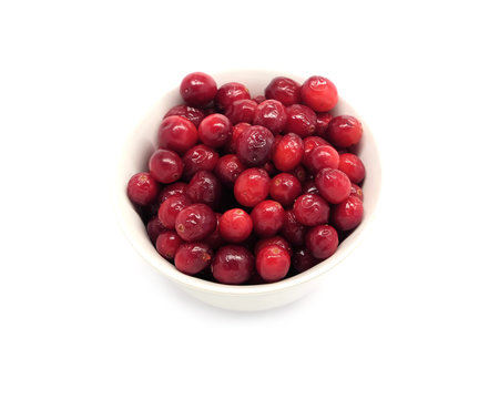 Cranberries in round white bowl isolated on white background indoor top view close up
