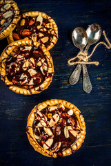 Mini tarts with nuts and caramel on a rustic background, top view, copy space 