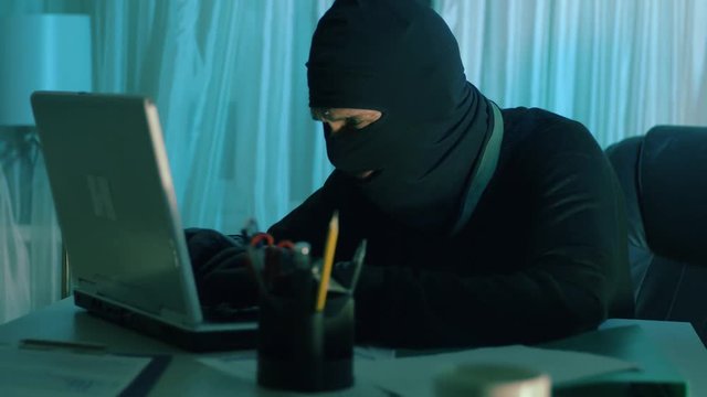 the thief hacker working on laptop in the night stealing data