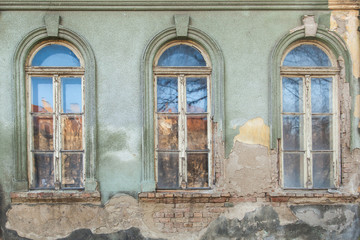 Fototapeta na wymiar three dilapidated windows on the old hobbled home