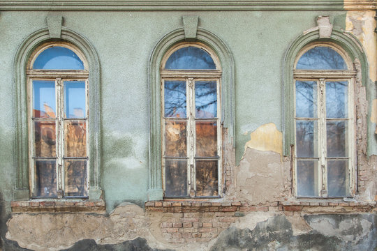 three dilapidated windows on the old hobbled home