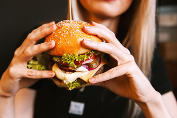 beautiful young, healthy girl holds a tasty big burger with beef cutlet - obrazy, fototapety, plakaty