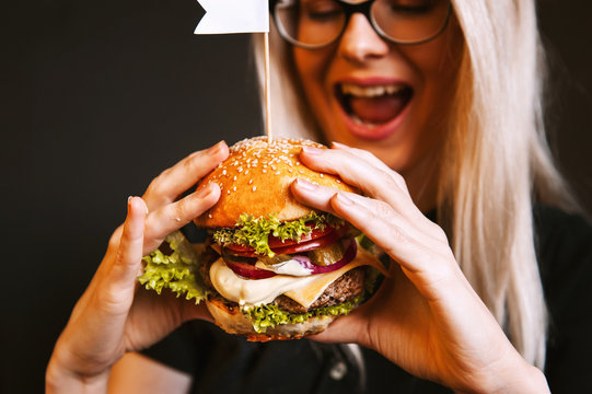 beautiful young, healthy girl holds a tasty big burger with beef cutlet
