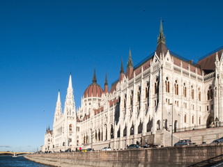 Fototapeta premium Daytime view of historical building of Hungarian Parliament, aka Orszaghaz, with typical symmetrical architecture and central dome on Danube River embankment in Budapest, Hungary, Europe. It is