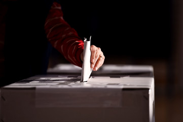 Hand casting a vote into the ballot box