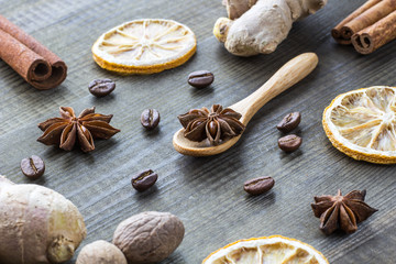 Fototapeta na wymiar star anise, dried lemon, cinnamon, ginger and coffee beans with wooden spoon on wooden table