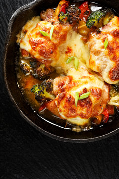 Roasted Chicken Thighs  Stuffed With Vegetables, Baked With Mozzarella Cheese, Top View, Black Stone Background