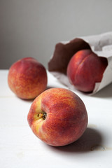 Apricot in a paper bag on a white wood table