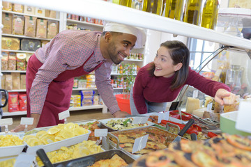 customer pointing to dish with sales assistant at deli counter
