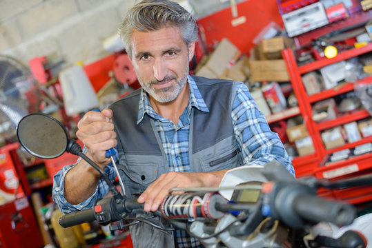 man repairing motorbike in a garage