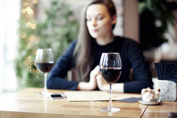 Woman drinking red wine in cafe and having rest near window