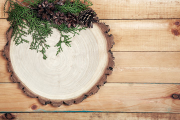 Board with leaves of thuja and pine cones on wooden background