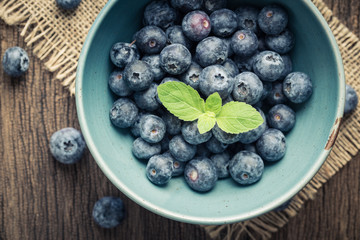 Blue berries in a blue bowl,On old wooden table top view.