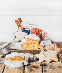 Piece of Traditional German Christmas cake Stollen with festive gingerbread star shaped cookies on rustic wooden table, selective focus, white background, copy space, vertical composition