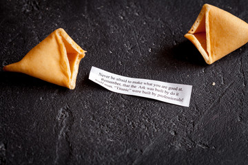 Chinese fortune cookie with prediction on dark background top view
