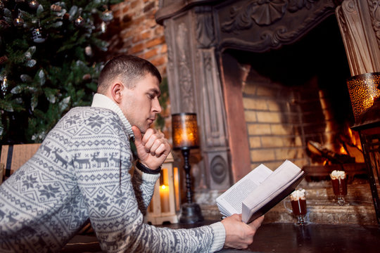 Man resting by the fireplace reading a book at home