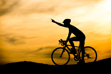 Obraz premium Silhouette of man with bicycle at sunset