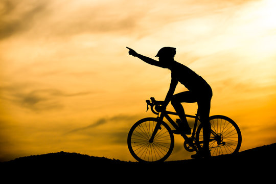 Silhouette of man with bicycle at sunset