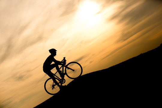 Silhouette of man with bicycle at sunset