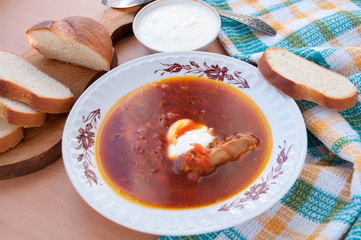 White bread lays on a plate beetroot soup with sour cream  