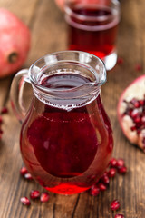 Portion of Pomegranate juice on wooden background (selective foc