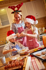 smiling children and mother baking Christmas cookies at home .