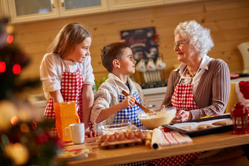 smiling children and grandmother preparing Xmas cookies.