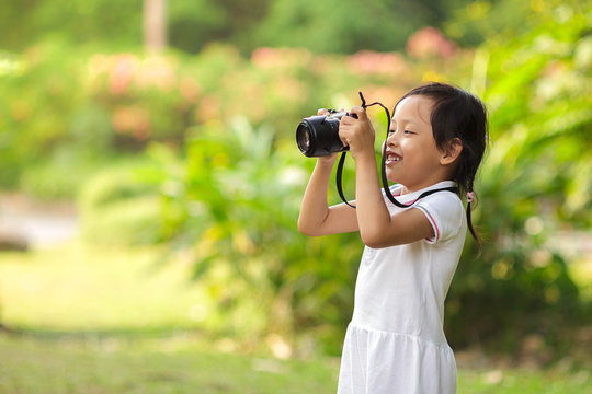 Beautiful child girl taking pictures at the nature field.