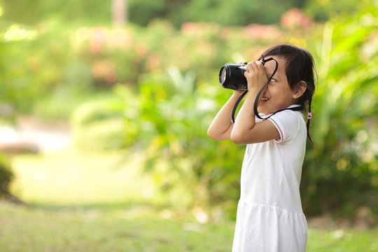 asian child girl taking pictures at the nature field.