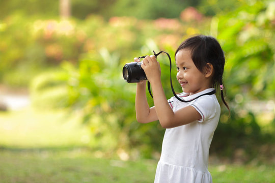 Beautiful child taking pictures at the nature field.