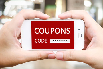 Hand holding smart phone with discount couopns code on screen