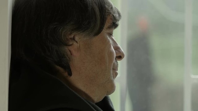 wistful and nostagic man looking out the window, leaned at the wall
