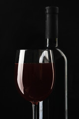 Glass of wine and a bottle on black background