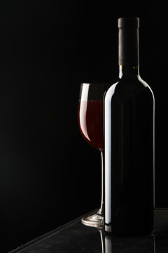 Glass of wine and a bottle on black background