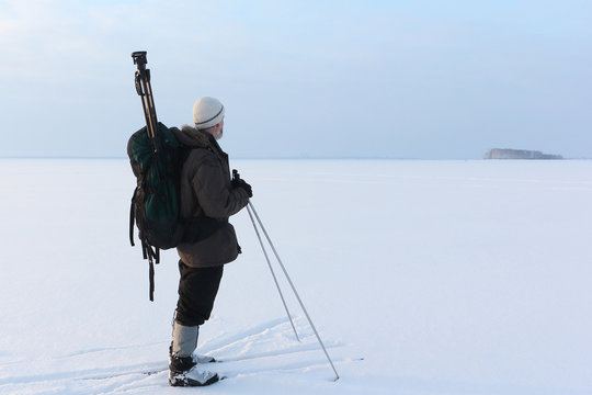 The man the photographer standing on snow on skis with a backpack and a tripod