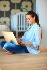 Young beautiful woman at home sitting on the floor with laptop