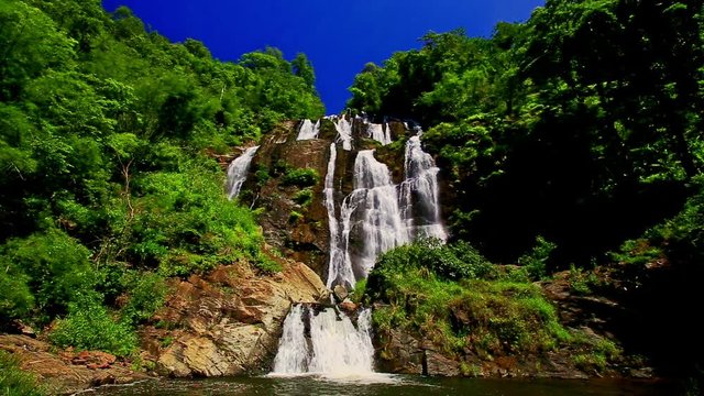 panorama of foamy mountain river high waterfall cascade and lake in tropical forest at bright sunlight