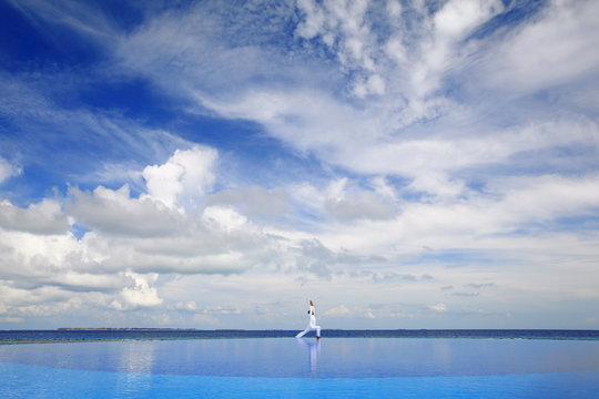 Young man meditating by infinity pool, Maldives