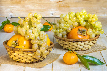 grapes, kaki and tangerine in wicker baskets