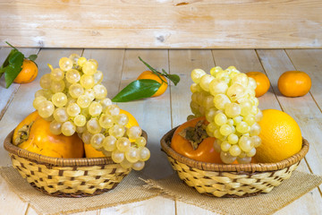 grapes, kaki and tangerine in wicker baskets