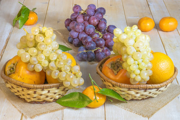 grapes, kaki and tangerine in wicker baskets