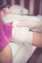 Child injured. Pediatrician doctor bandaging child's knee. Vintage tone.