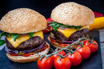Homemade beef burgers on a black slate background.