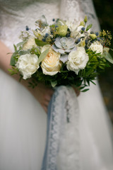 blue and white bouquet with lace ribbons in hands of the bride