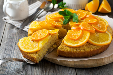 Fototapeta na wymiar Orange and mandarin cake with polenta, upside down on the old wooden background. Selective focus..