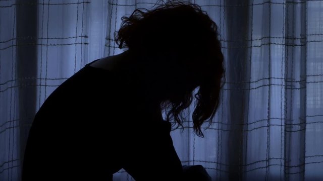desperate woman wheeping in a dark room, isolated from the world